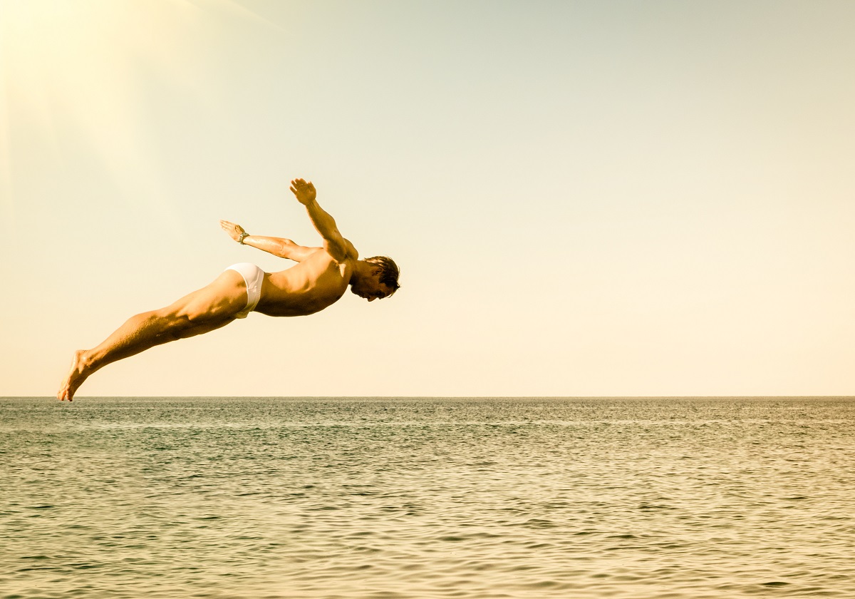 Cliff,Diver,Jumping,In,The,Sea,Against,The,Sky,At